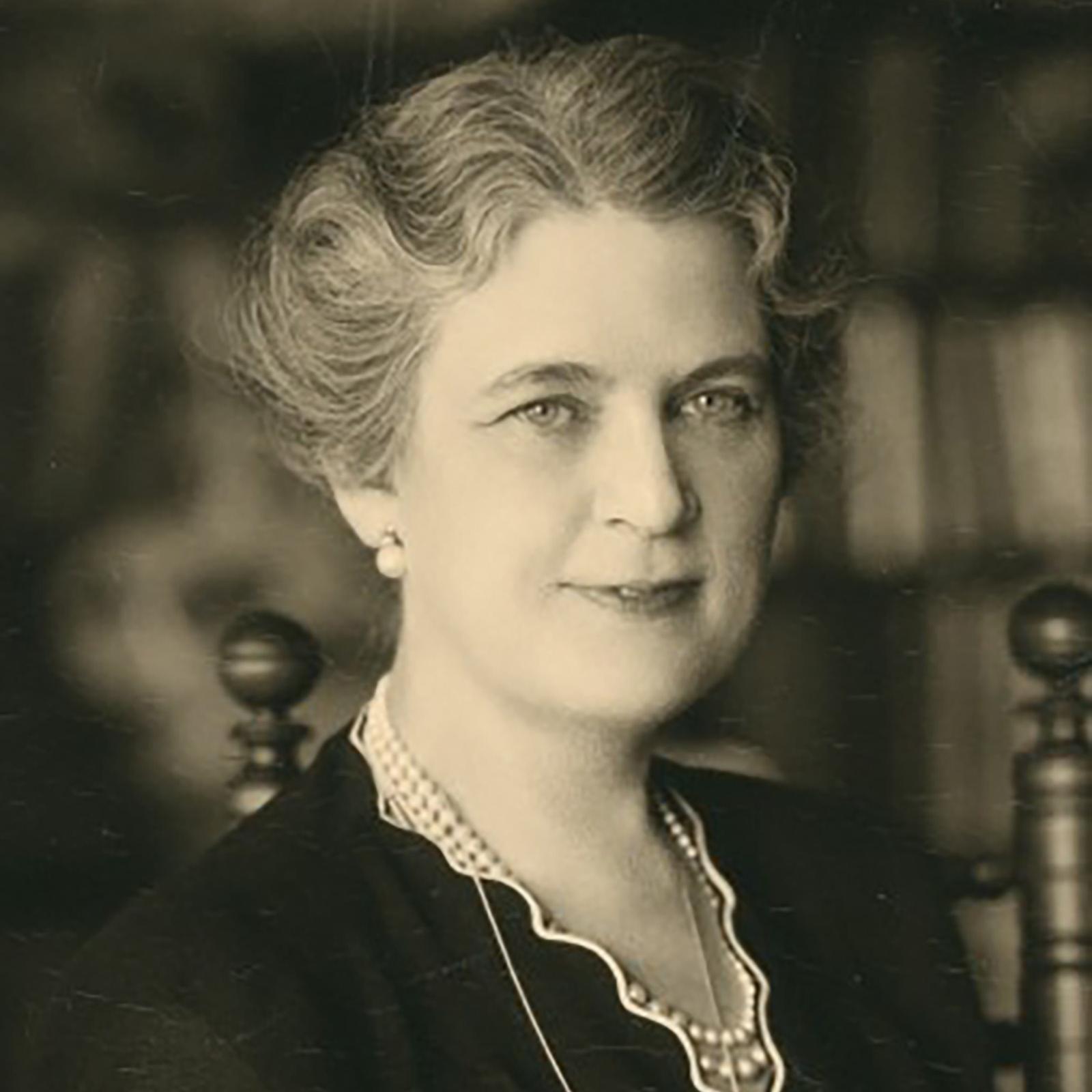 A seated woman wearing a dark dress.