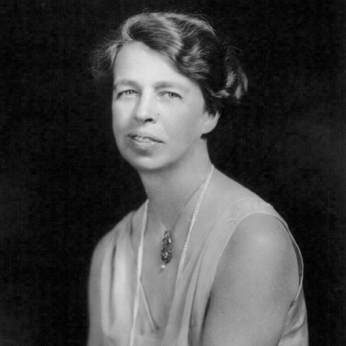 A woman wearing a gown and long string of pearls.