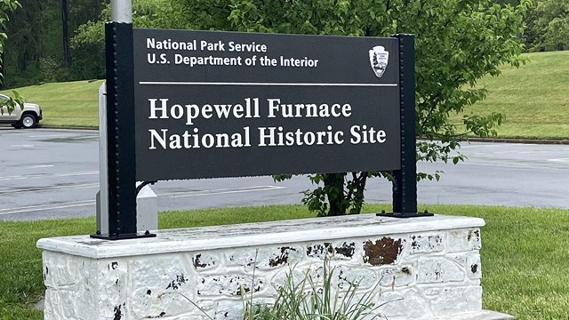 large black sign with white letters reads Hopewell Furnace National Historic Site