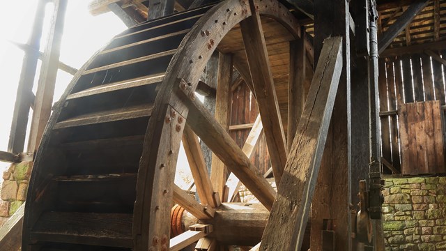 Wooden water wheel powers bellows.