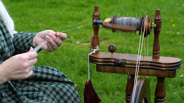 Feeding wool into spinning wheel.