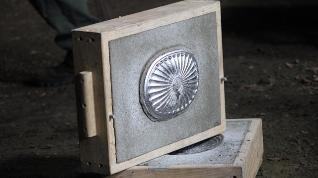 A metal plate cast in a sand box. 