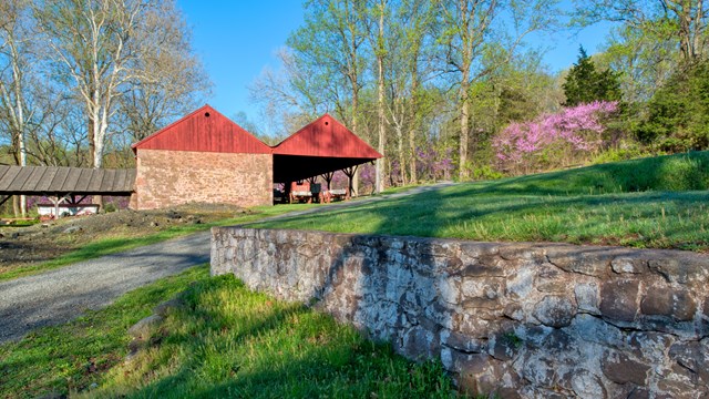 Stone building with red gables and a shed attached. 