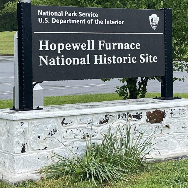 large black sign with white letters reads Hopewell Furnace National Historic Site