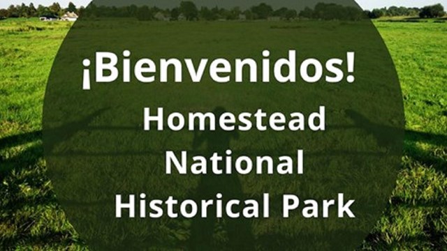 Grassy field with text "Bienvenidos Homestead National Historical Park"