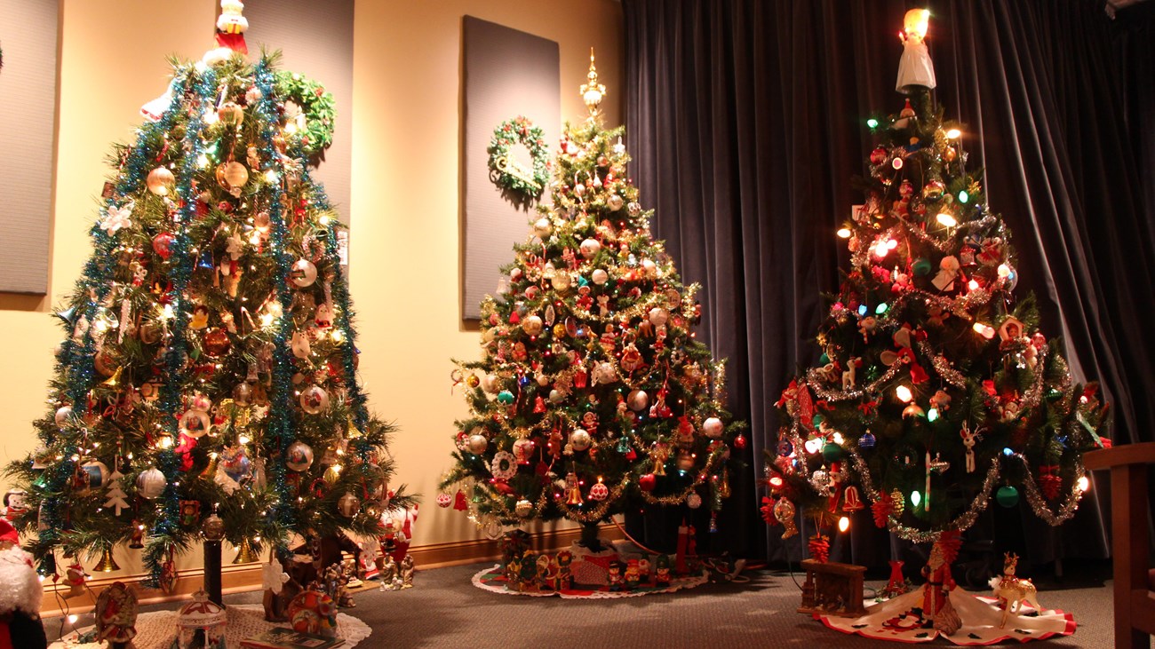 Three Christmas trees decorated with ornaments symbolically tied to homesteading cultures.