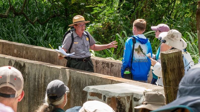 National Park Service staff talking to a group of visitors on an aqueduct.