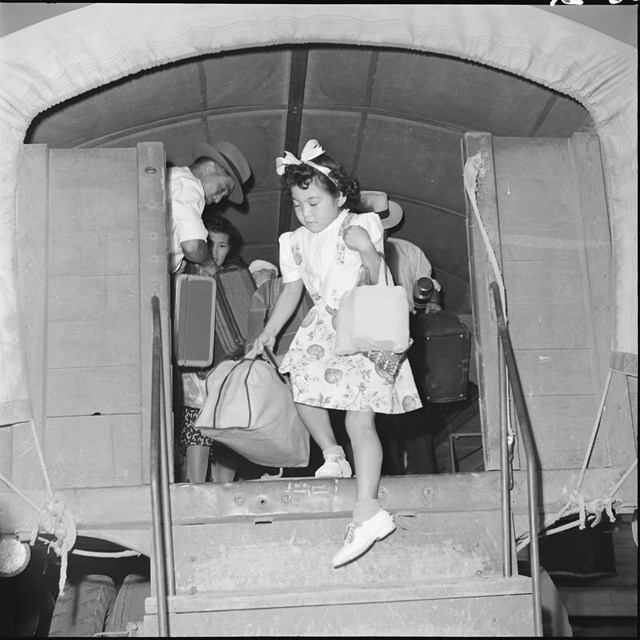 A Japanese girl exiting a truck with her suitcase