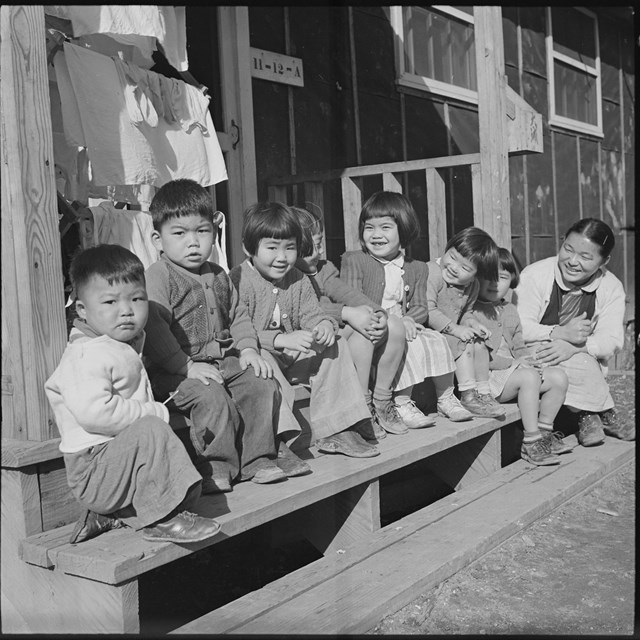 Japanese children sitting outside a building in a line