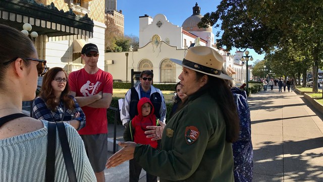 A ranger addresses a group of people in front of the Fordyce Bathhouse.