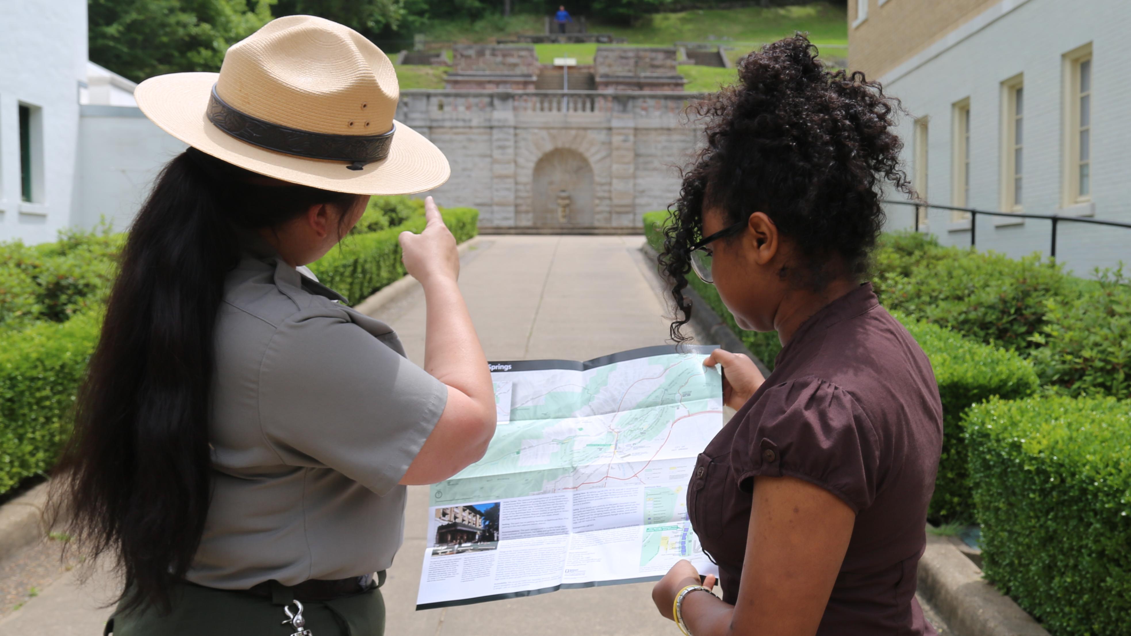 A park ranger uses a park map to provide a visitor with directions