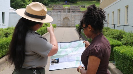 A park ranger uses a park map to provide a visitor with directions