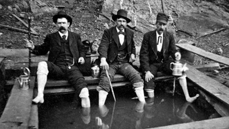 Three men from the mid-1800s are soaking in Corn Hole Spring.