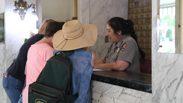 Visitors receive information from a park ranger at the visitor center front desk