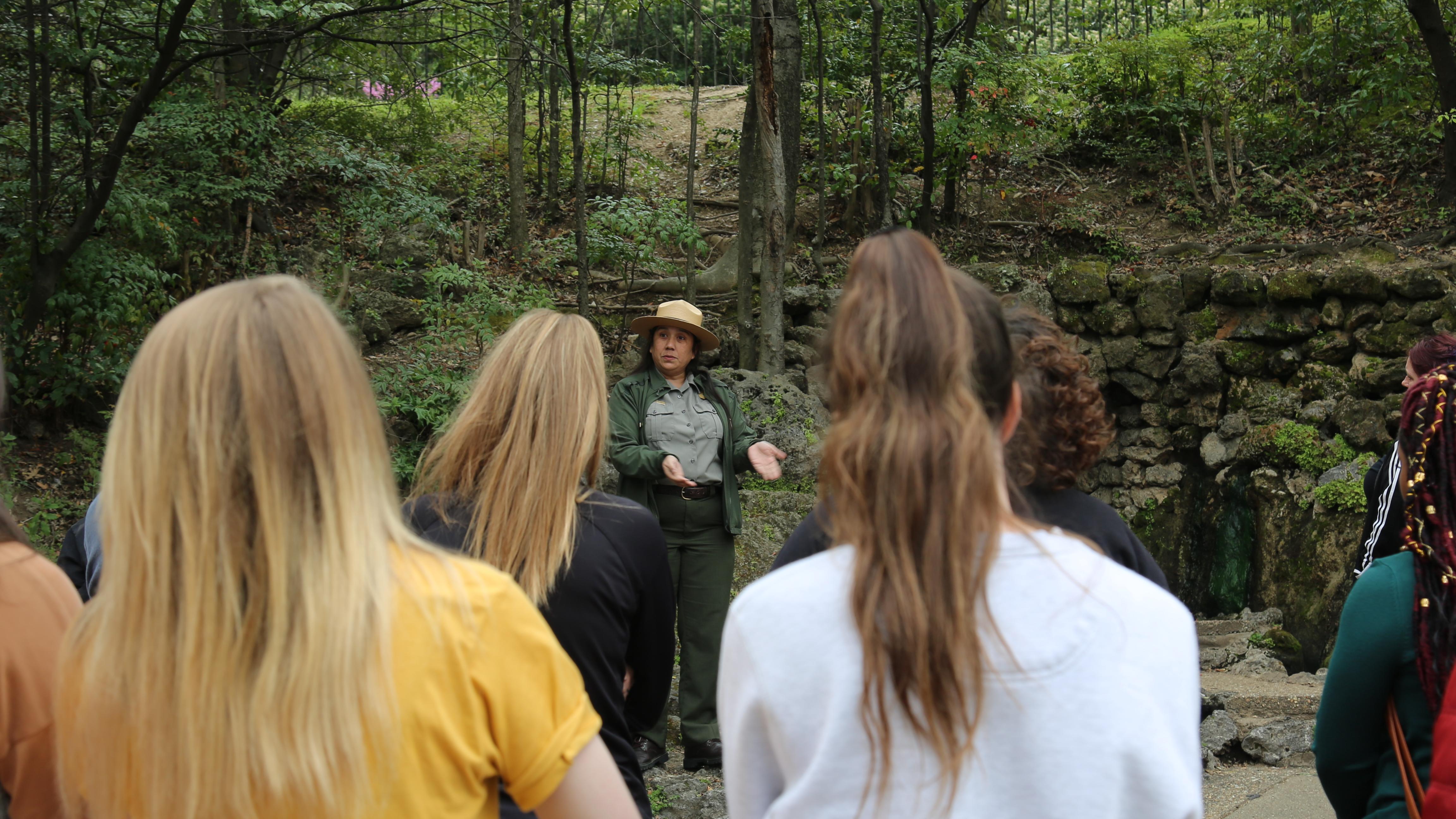 A park ranger delivers a program to a high school group in front of a thermal spring.