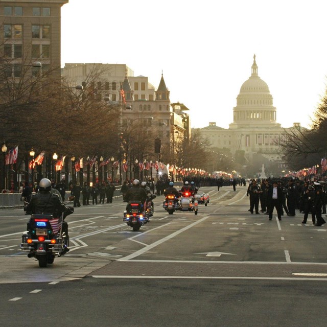 Police on motorcycles riding a  parade route towards the US Capitol building