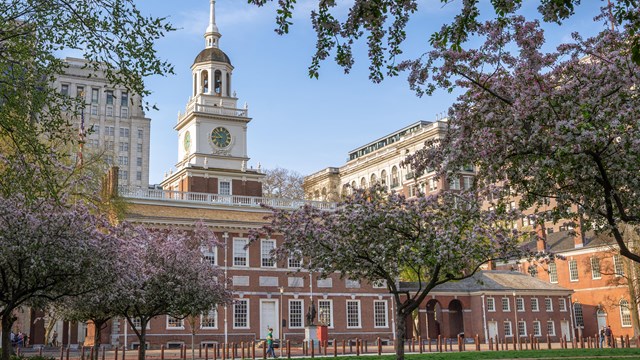 Two story 18th century brick building with a white cupola and bell tower.