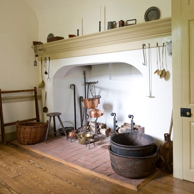 Color photo of a large open hearth with iron and copper cooking pots.