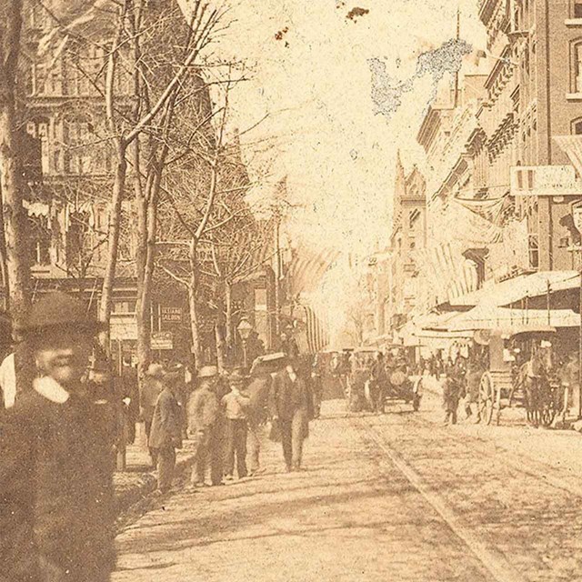 Sepia photo from 1865 showing people on a city street.