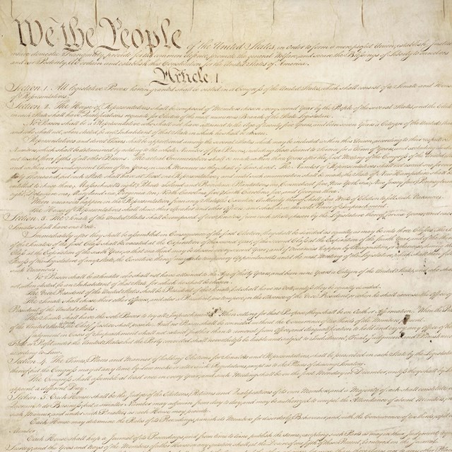 Color image of page one of the U.S. Constitution, showing brown ink on yellow paper.