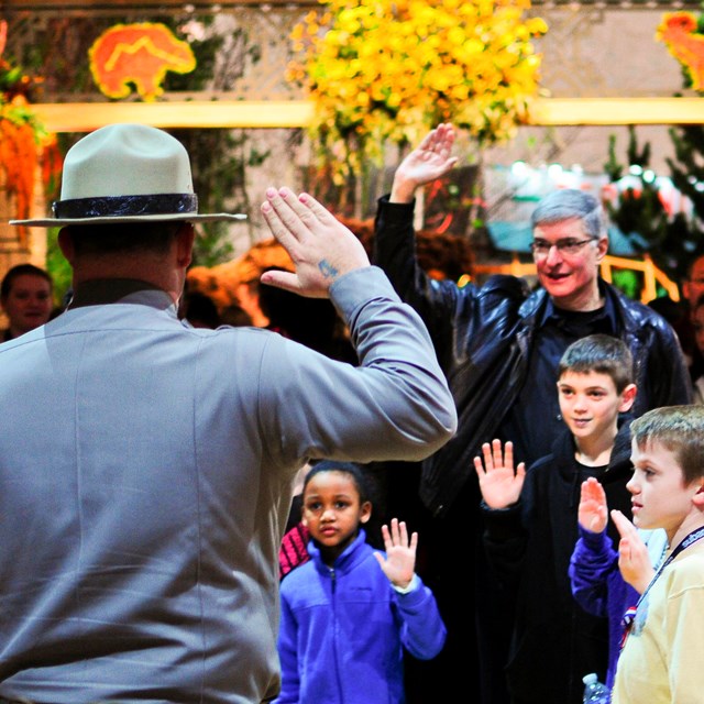 Color image of a park ranger holding up his hand as he swears kids in as junior rangers.
