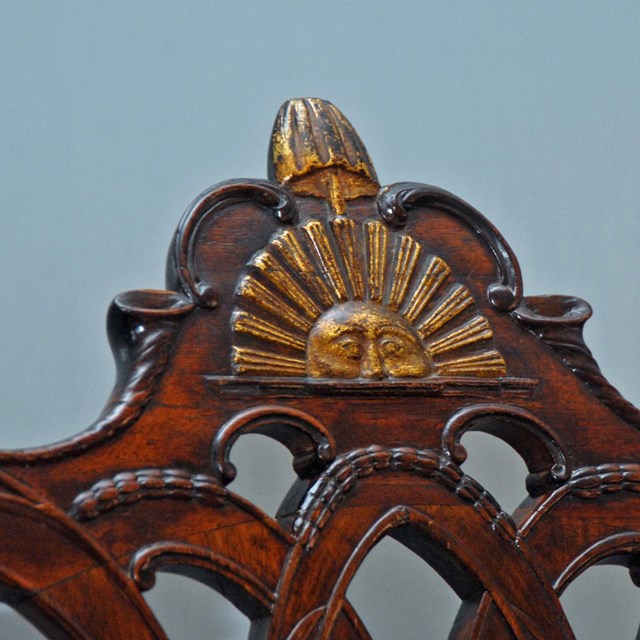 Detail of the top of the Rising Sun chair showing the carved half sun with liberty pole and cap.