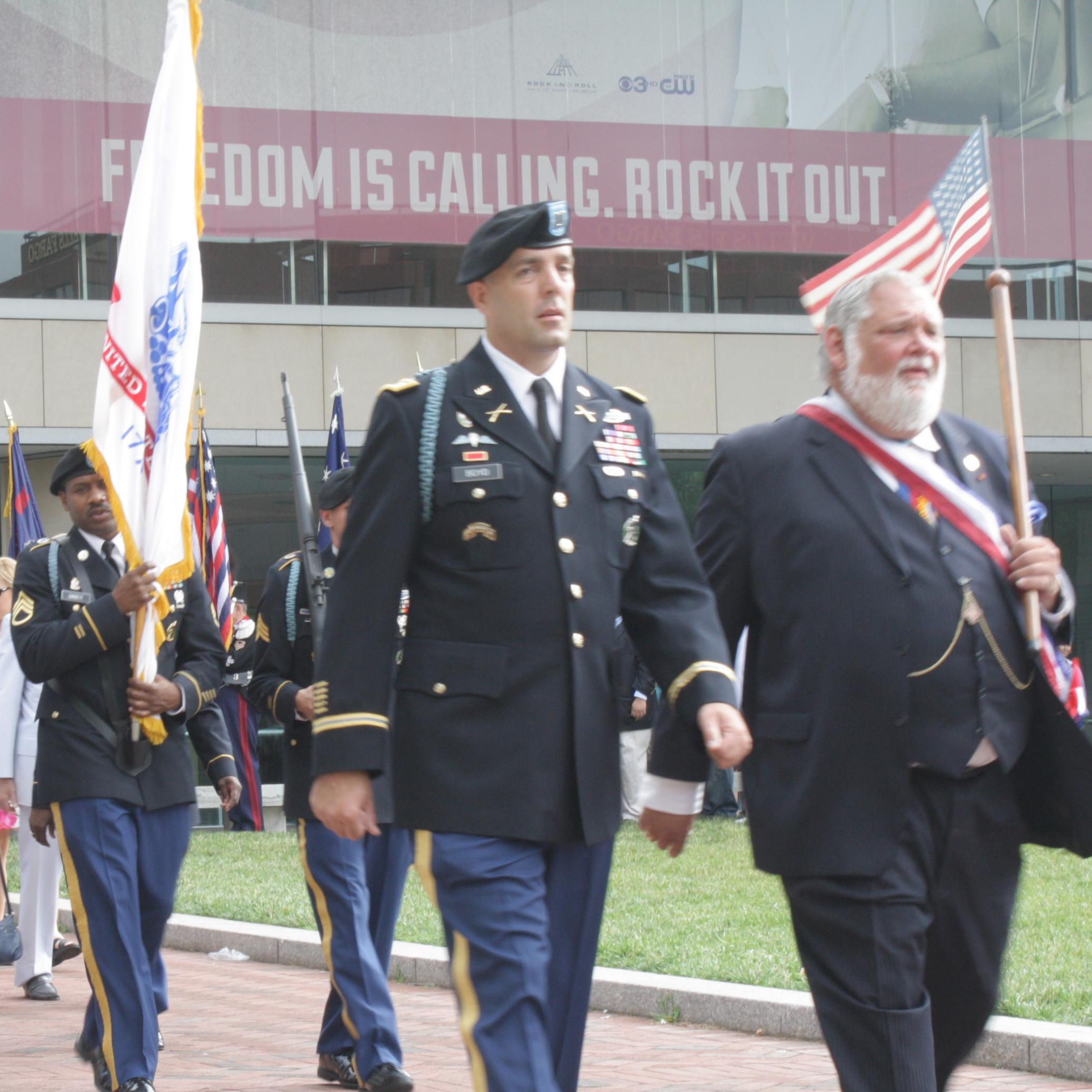 Color photo of men in military uniform marching near the National Constitution Center