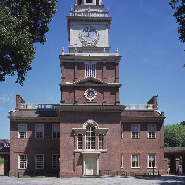 Color photo of a large, two story red brick building with Palladian style window and clock tower.