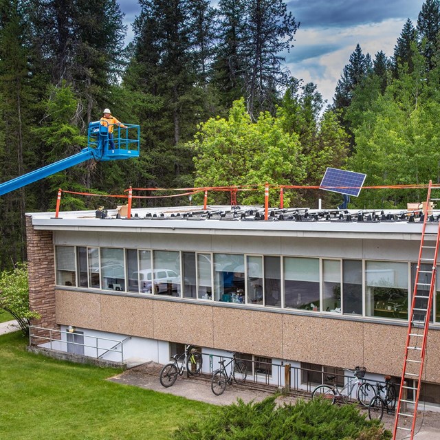 Lift carrying workers installing solar panels on top of a headquarters building's roof