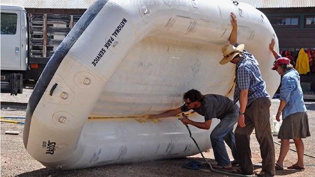 three people clean an inflatable raft