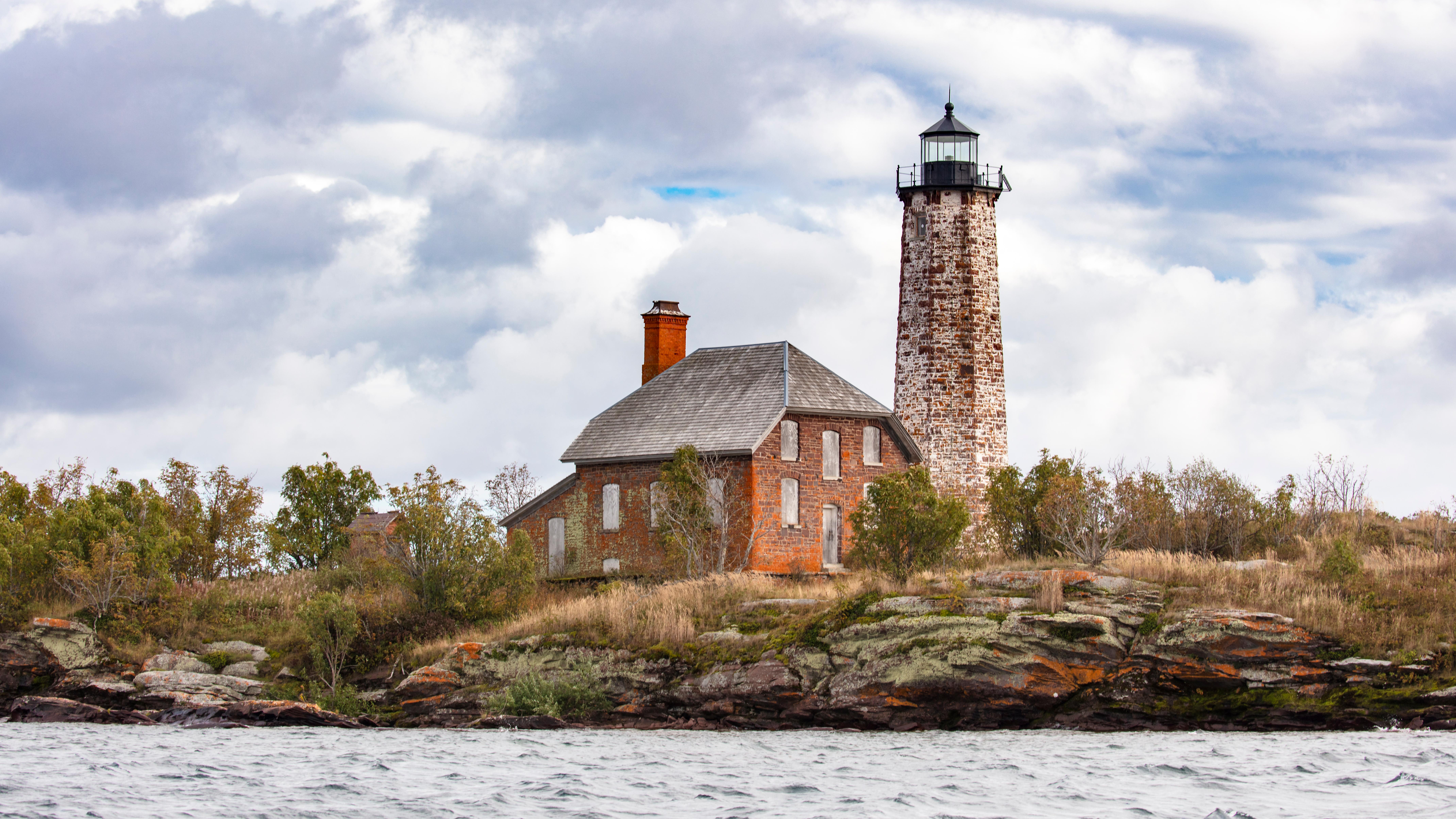 just a small piece of blue jetting through the clouds atop a lighthouse on a rocky island