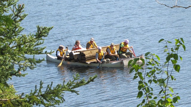 Maintenance and trails crew moving materials via canoe across the harbor. 
