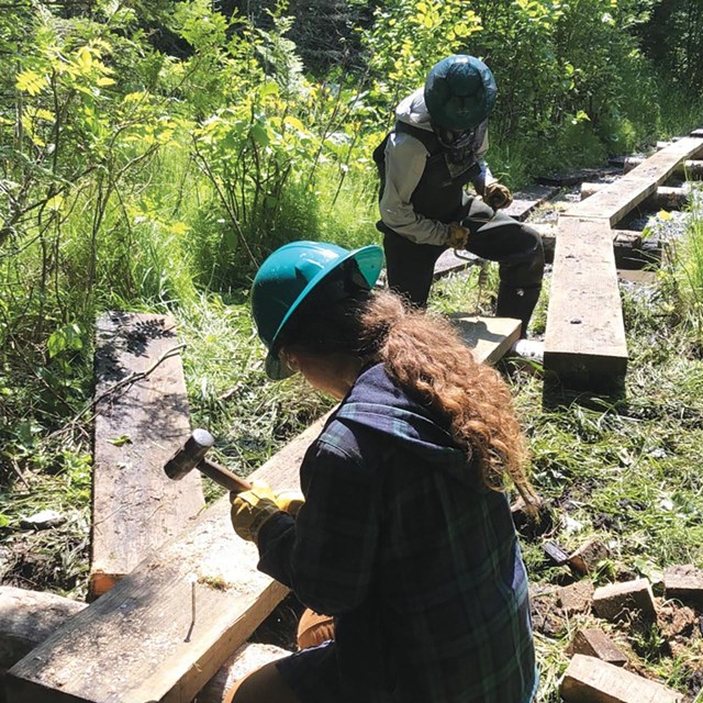 Two Wiscorps members help build a boardwalk on a trail. 