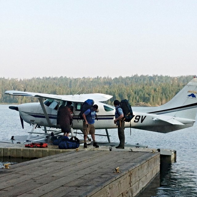 A white and red seaplane sits parked on a floating dock.