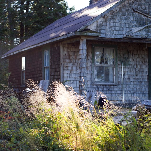 Historic cottage with weathered wood siding sits on Washington Island. 