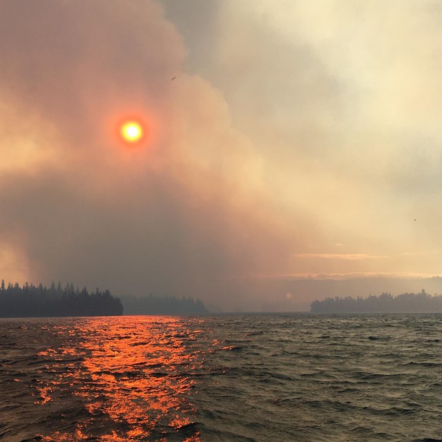 Smoke rises from Isle Royale. The sky is orange. 