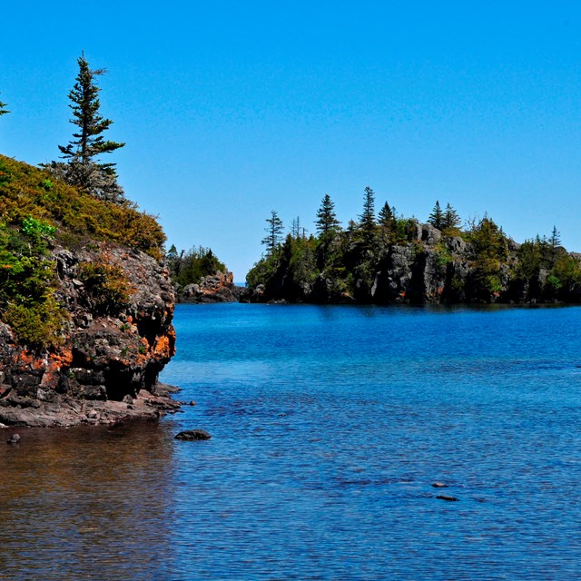 rocky outcropping towers over lake edge