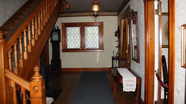 Photo of entry hall, including original woodwork and reproduction wallpapers from 1880.