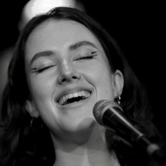 Woman smiling while singing on a microphone