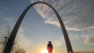Ranger standing under the Arch at sunset