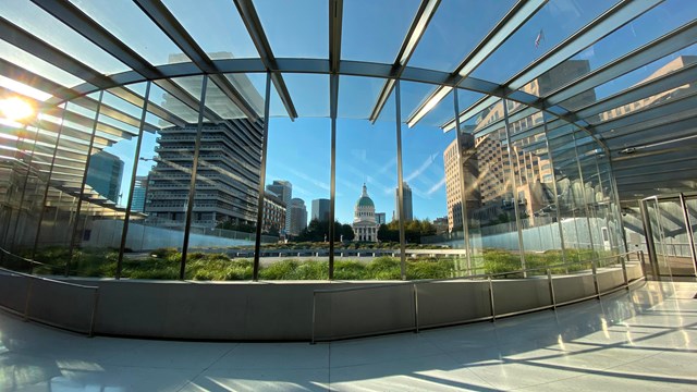 the glass entrance to the visitor center at the Arch with the Old Courthouse in the distance