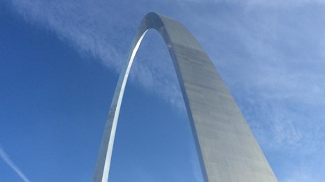 looking up a the Gateway Arch against a blue sky