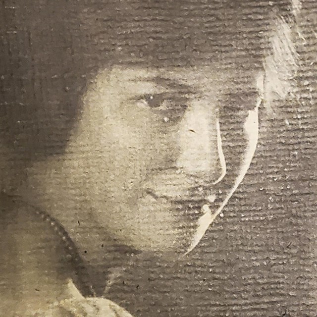 Black and white portrait shot of a woman smiling slightly at the camera over her shoulder.
