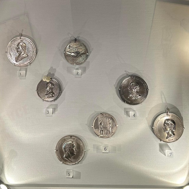 Several silver medallions behind glass in a museum display case