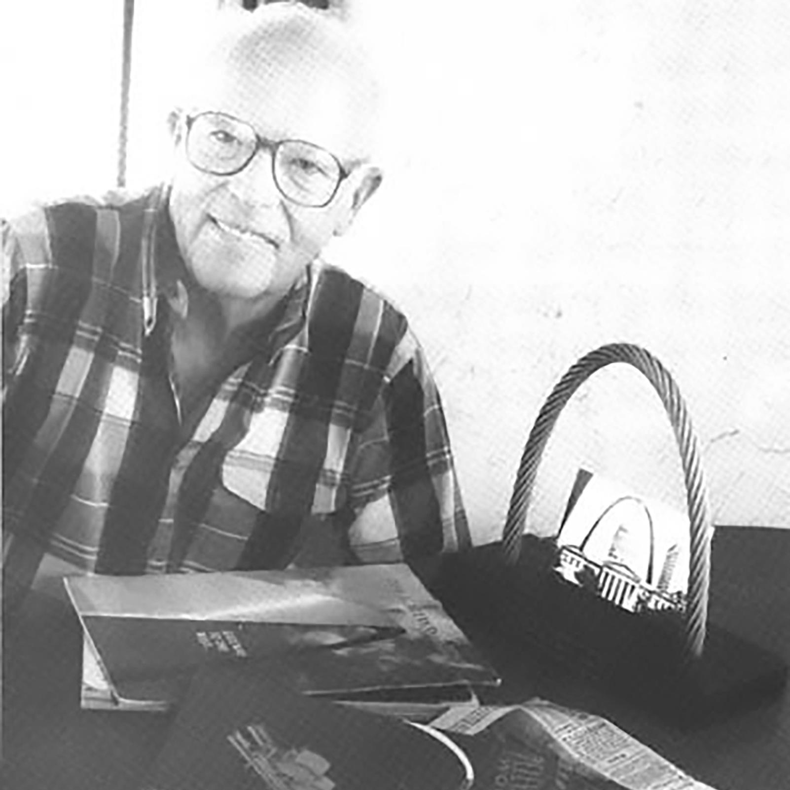 A black and white photo of an elderly smiling man wearing glasses