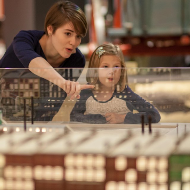 a woman and child examining a model of the St. Louis Levee