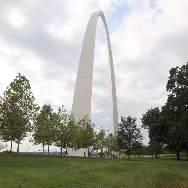 The gleaming stainless steel upside-down U of the gateway arch, with green grass in the foreground