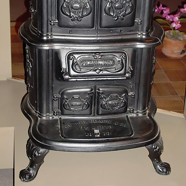 An old-fashioned black stove with claw feet on the bottom and engravings on the front