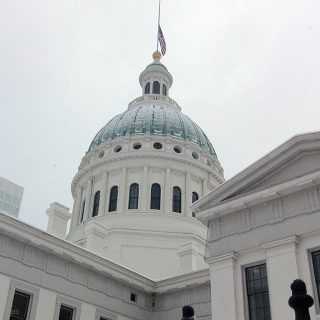 The green dome of St. Louis's Old Courthouse, covered in snow behind a snowy fence.