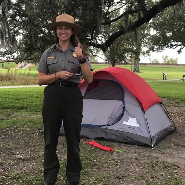 park ranger stands in front of contemporary tent